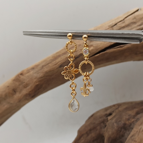 Przejdź do produktu Kolczyki Fleur de Lille, złocone, asymetryczne, wiszące, na sztyfcie, zawieszki lilijki, kryształ górski, kamień księżycowy